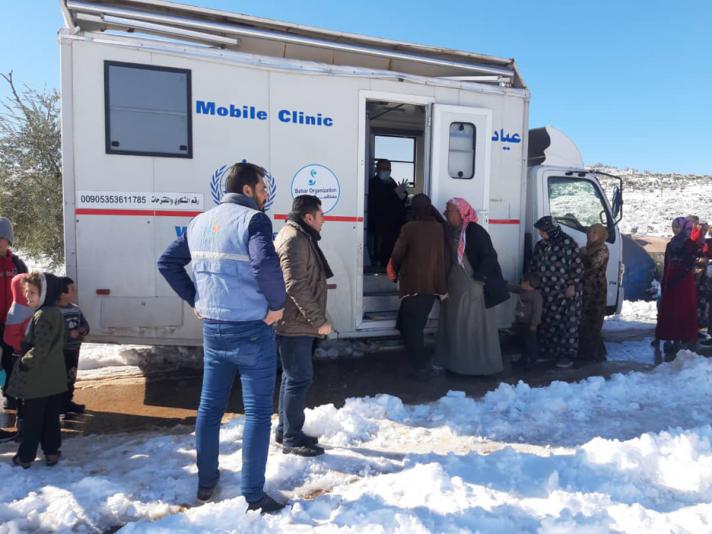 People cueing in front of a mobile clinic van