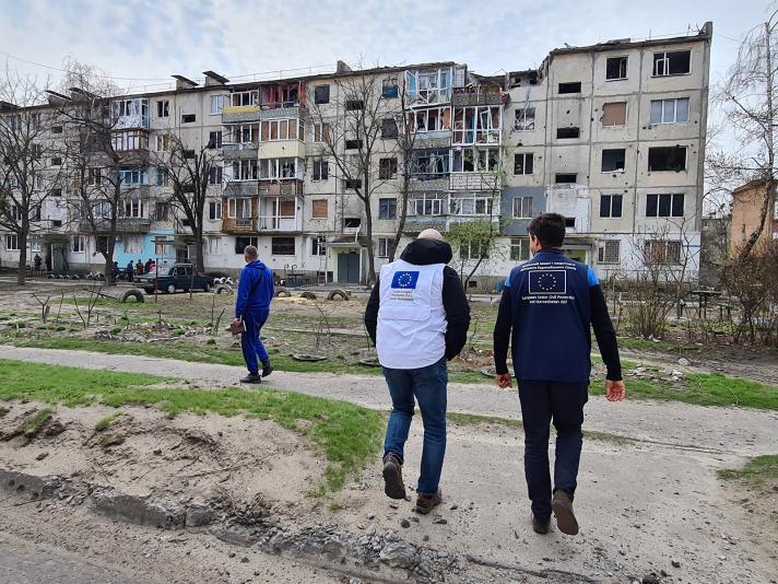 EU humanitarian aid staff looking at destroyed appartment building