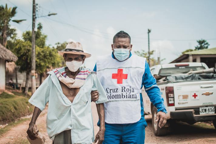 Aid worker with an elderly person walking in the street