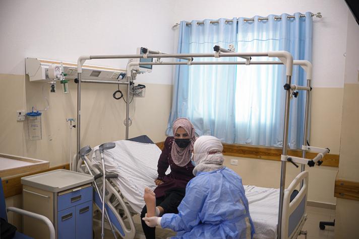 A nurse holding Mayada's foot in a hospital room