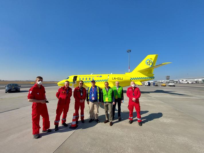Group of civil protection colleagues in front of the yellow medical evacuation plane