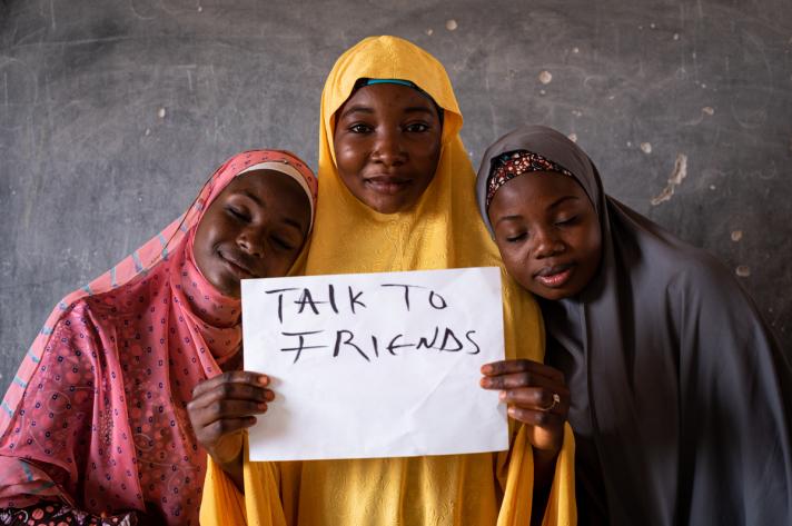 3 girls holding up a sign 'Talk to friends'