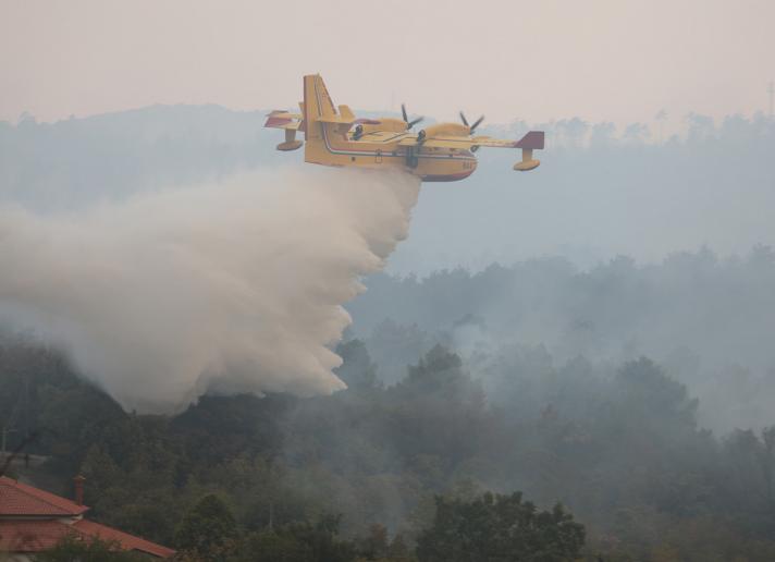 Firefighting plane dropping water over a burning forest