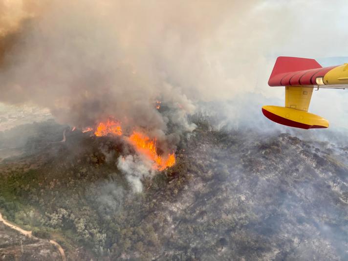 View from within a firefighting plane of a fire on top of a hill 