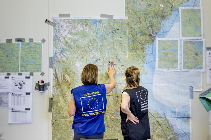 2 ERCC colleagues in front of a map hanging on a wall