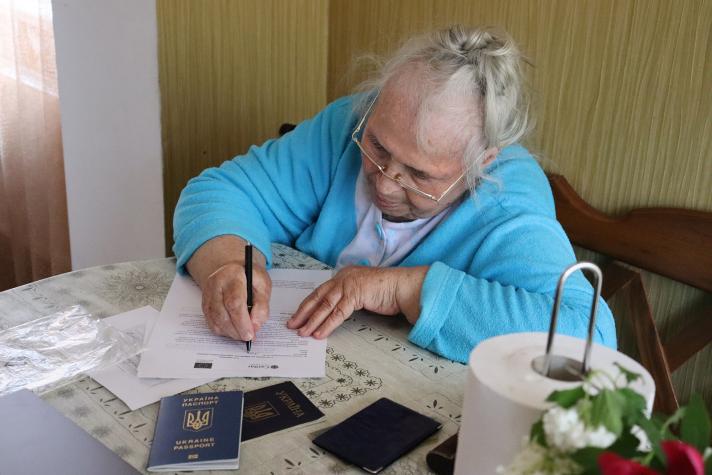 Ludmila sitting at a table while writing on a document