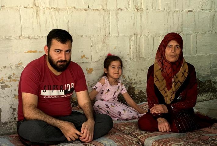 Mother and father sitting on a carpet with inbetween them their daughter