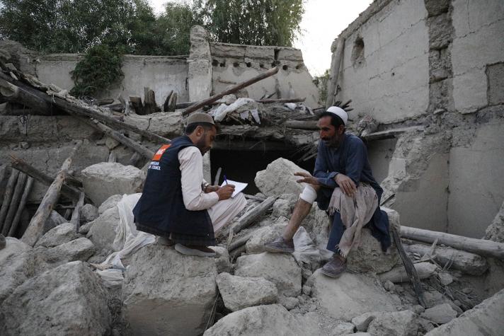 Aid worker sitting on the debris of a building talking to Shafi