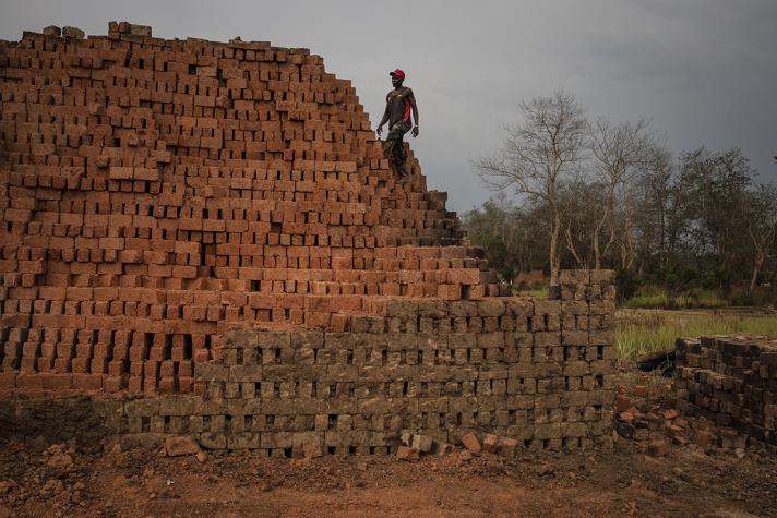 A brick maker looks at a distance to a pile of bricks