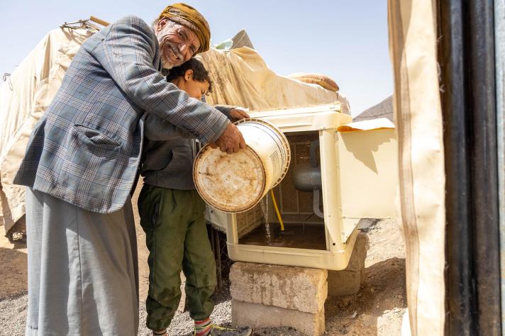 Bashir’s father with his grandson fills his air conditioner with the required water. 