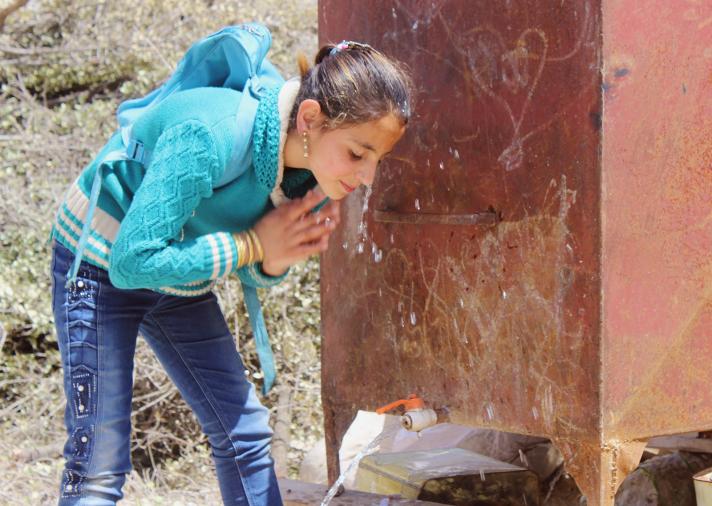 Layla, one of Abu Reza’s daughters, is washing up at the water tank GOAL installed in front of the family’s house on her way back from school.
