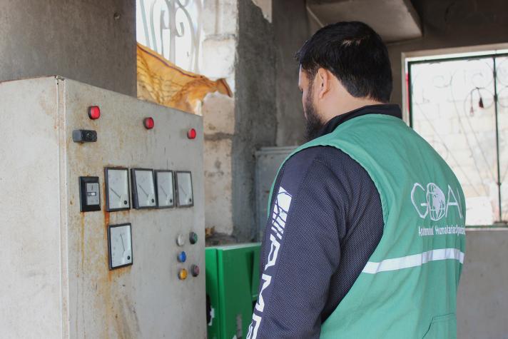 A GOAL WASH engineer is examining the board at the water pumping station serving Al Baliya Village.