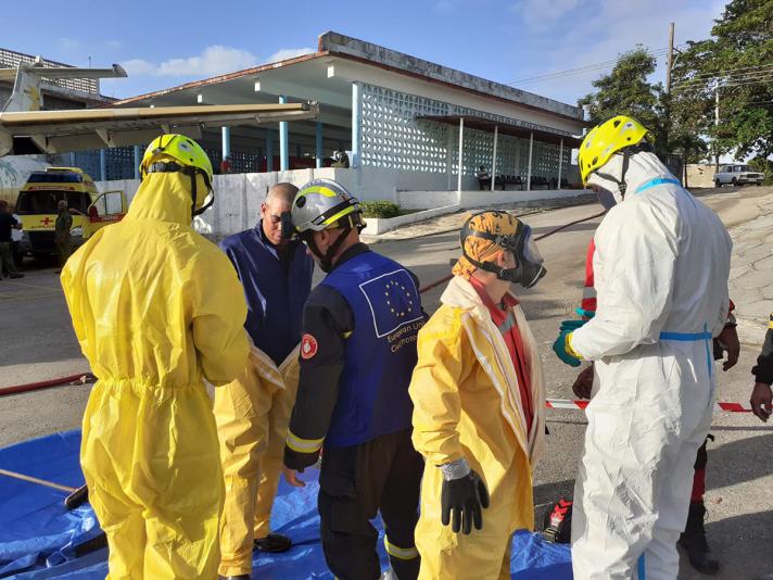 People getting decontaminated by colleagues in yellow and white suits.