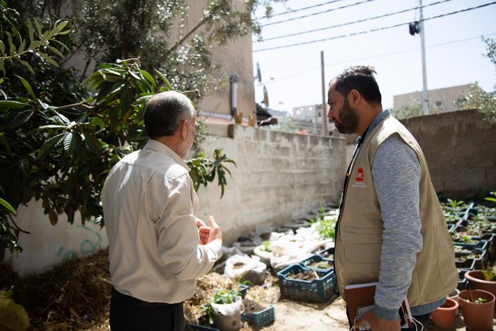Wajeeh and an aid worker in his garden filled with crates of growing vegetables