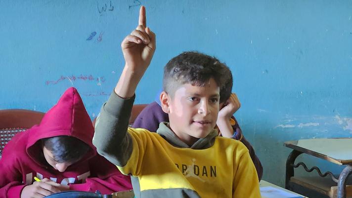 Mohammed raising his finger in a class room.