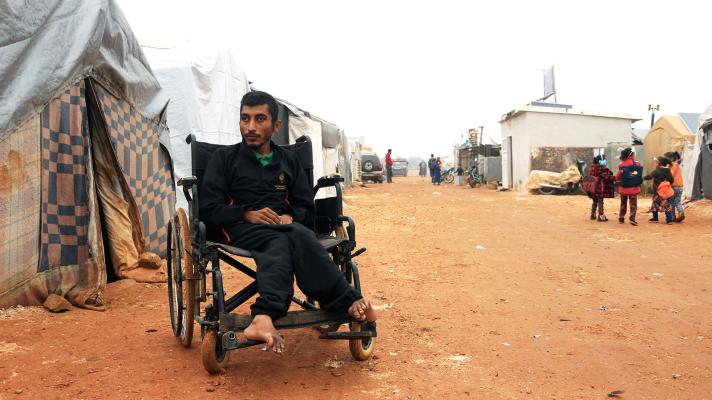 Person sitting in a wheelchair in front of a shelter tent