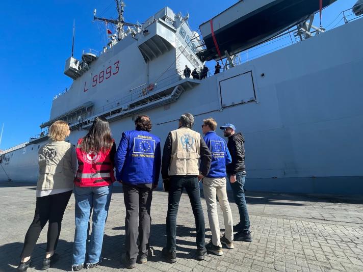Group of aidworkers, seen from the back, looking at a cargo vessel.