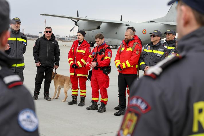 Several rescue workers and a search dog, in the background a plane.