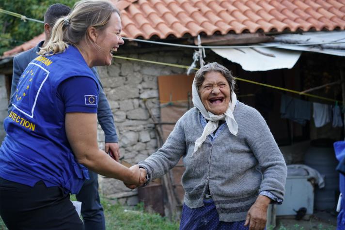 Ingeborg shaking hands with an elderly woman in front of her house