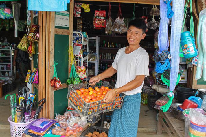 Ndau La Raw outside a small shop, holding a basket of fruit
