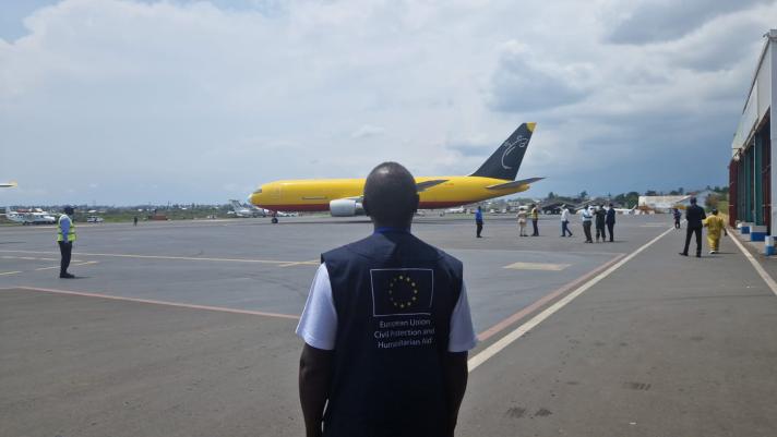 Aid worker in front of a plane on the airport strip.