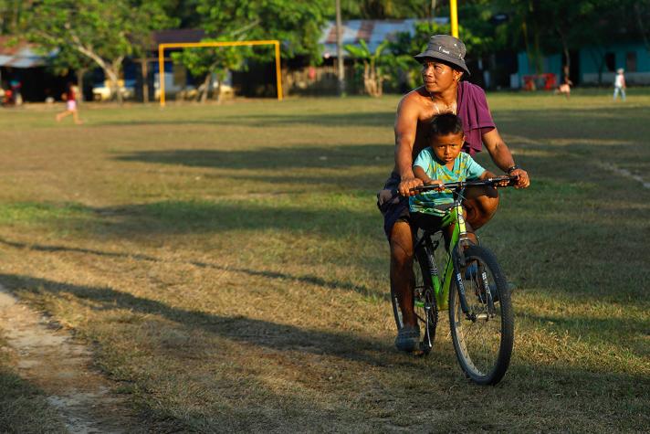 Person with child on a bike near a sport terrain.