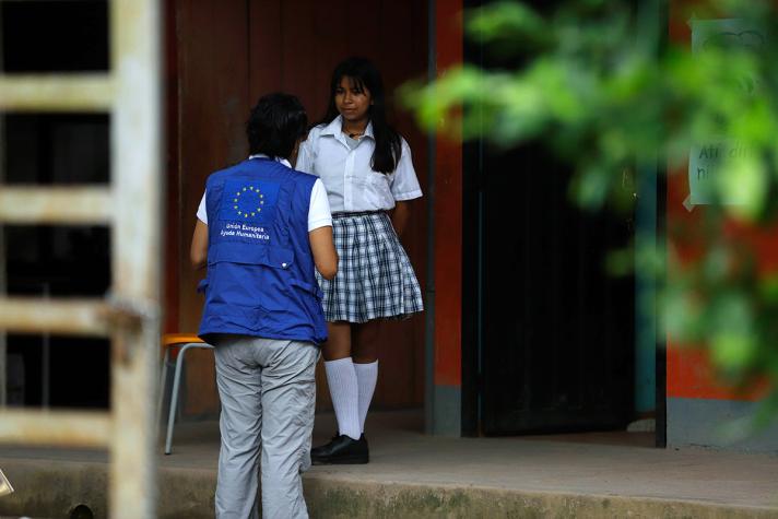 Aid worker talking ot a girl attending school.