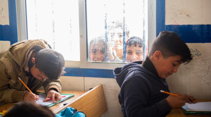 Students peek through the window of a classroom