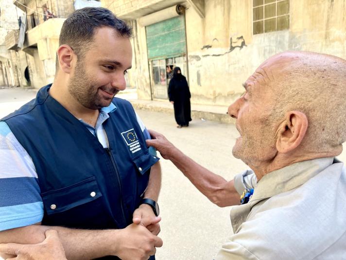 Aid worker talking to an elderly, standing in a street.