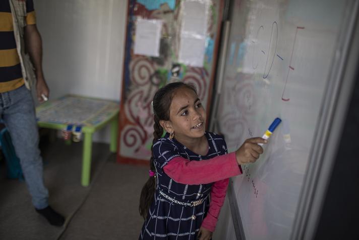 Samah with a pen at a whiteboard.