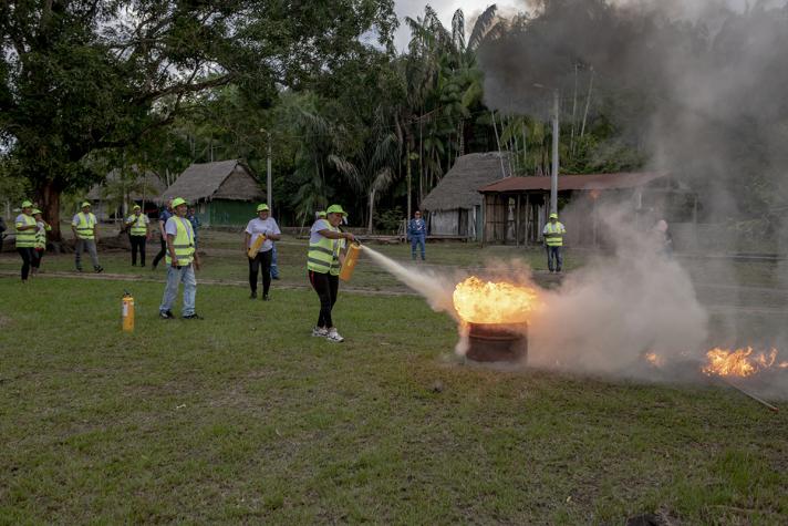Fire extinguish excercise with several people and a burning drum in the middle.