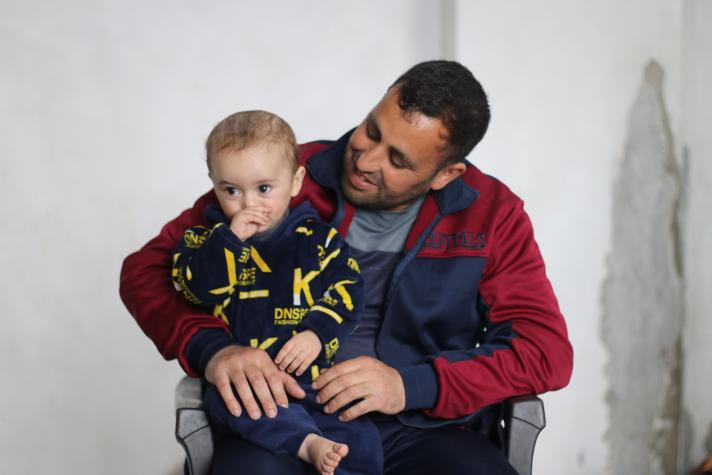 A man sitting on a chair, holding his son in his arms.