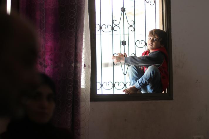 Bayan, 5, sits by the window of the family home.