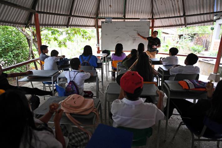 View of a class room with students. A teacher in front at the white board.
