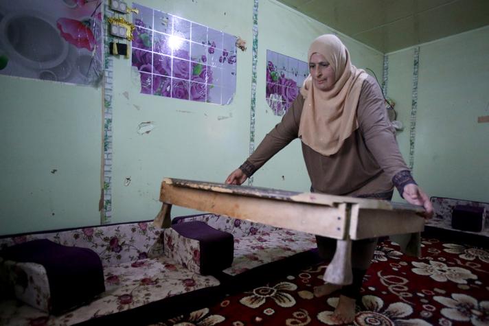 Fadwa moving a low table in her house.
