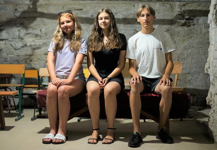 Anna, Anastasiia, and Maksym sitting on chairs.
