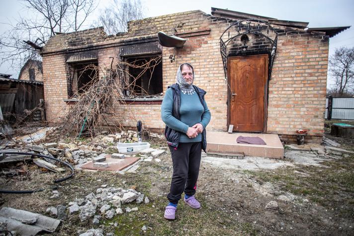 Oksana in front of her destroyed house.