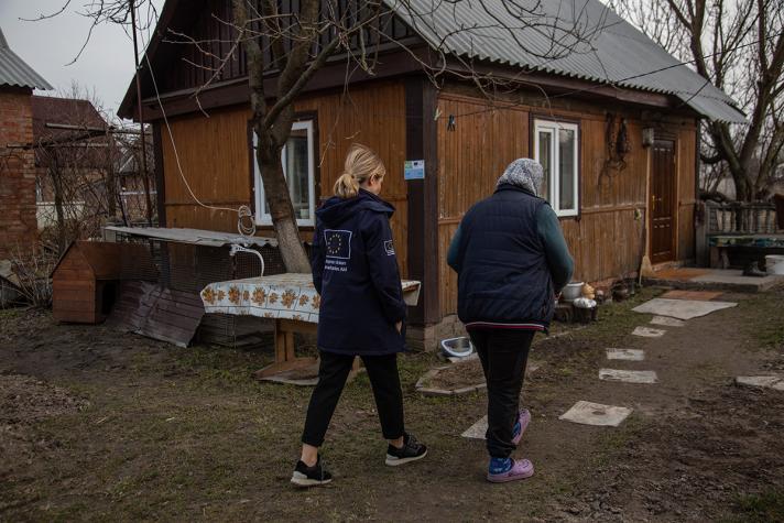 Oksana and an aid worker walking towards her garden house.