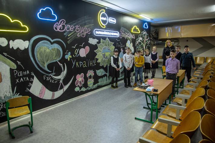 View inside a child friendly shelter. The walls have drawings and some neon lights in the shape of clouds.