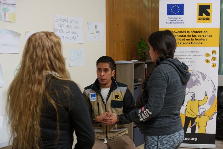 An aid worker talking to refugees in an office. In the background banners with information.