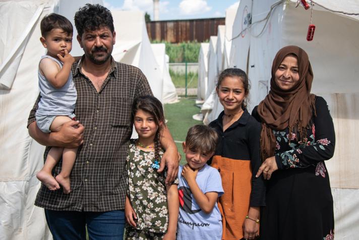 A family in front of shelter tents.