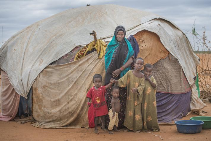 Amina and her family in front of a shelter tent.