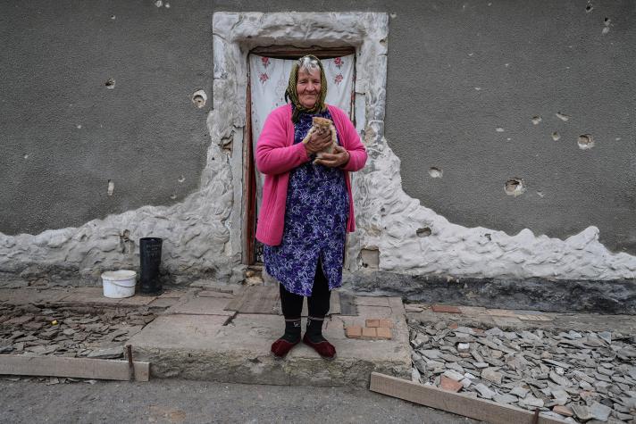 Olha standing in front of her house. Holding a kitten in her hands.