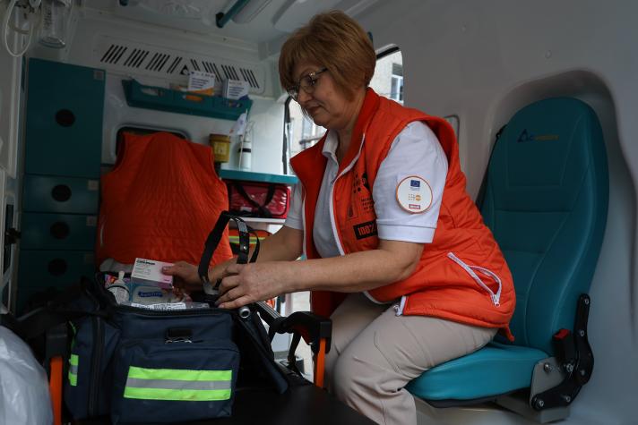 Dr Natalia Pushlenkova sitting on a blue chair in the back of the ambulance while preparing a medicine kit.