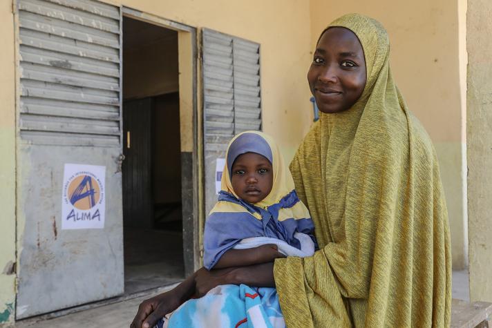 Hadja and her daughter in front of a window at the health centre.
