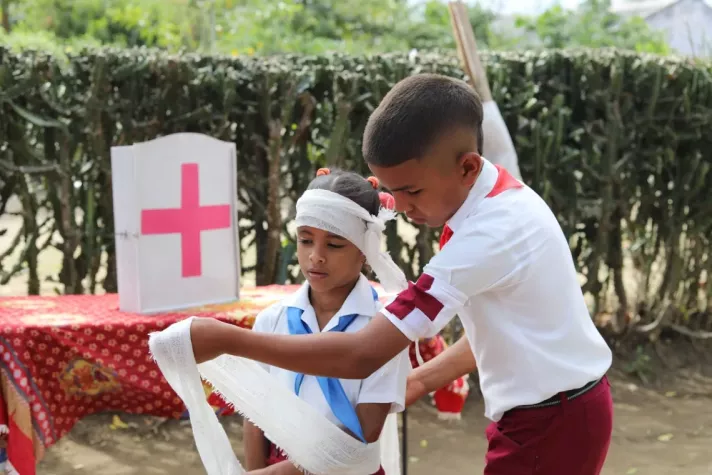 2 children practicing applying a bandage to an arm.