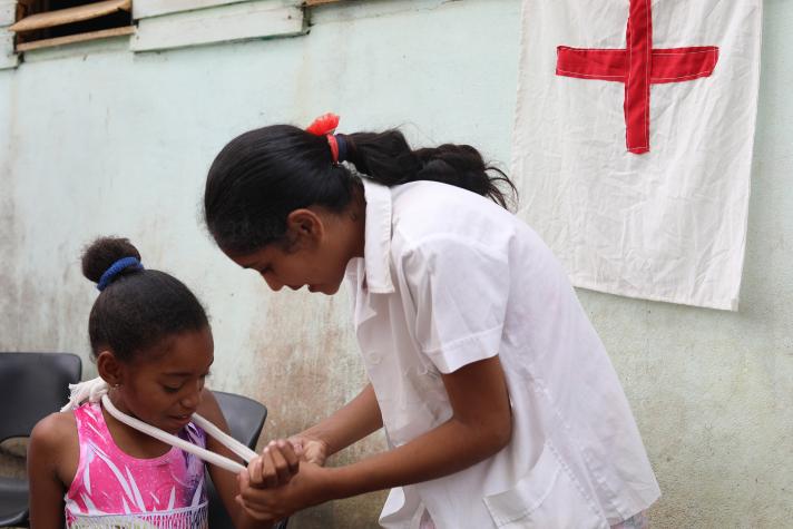 A nurse showing a little girl how to put on a bandage.