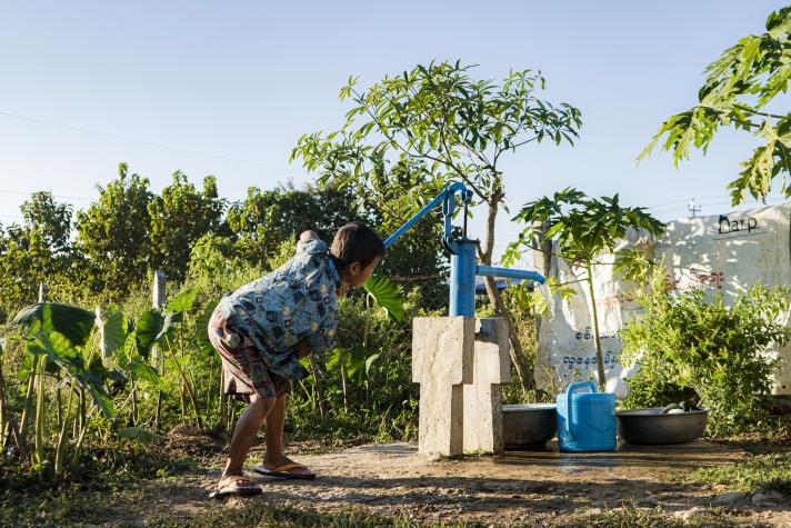 A boy pumping water from a water pump.