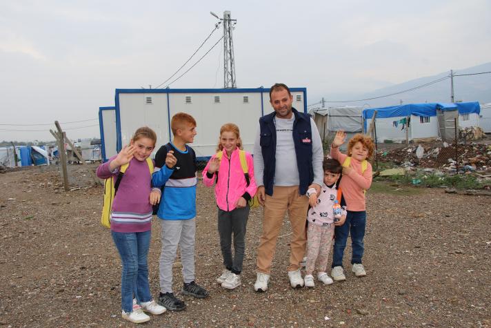 The whole family standing in front of the container school.