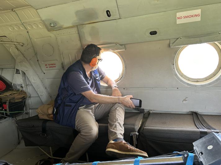 An aid worker seen from inside the helicopter looking out a round window.